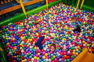 enfant jouant dans une fosse à balles colorée. garderie aire de jeux intérieure. piscine à balles pour les enfants. jardin d'enfants ou salle de jeux préscolaire. photo