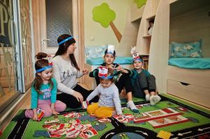 famille heureuse avec quatre enfants jouant au jeu devinez qui tout en s'amusant à la maison. photo