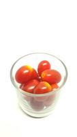 Tomates cerises en verre isolé sur fond blanc photo