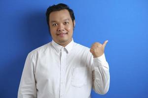 portrait d'un jeune employé de bureau heureux asiatique souriant et pointant vers la présentation de quelque chose de son côté photo