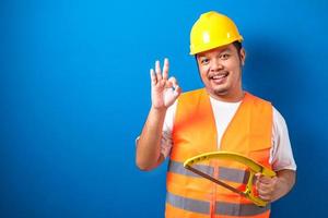 Fat Asian Construction Worker portant un gilet de sécurité orange et un casque montrant un signe correct photo