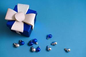 coffret cadeau bleu avec des boules de noël sur fond bleu photo