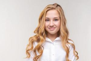 jeune femme blonde vêtue d'une chemise blanche en relief, se tient détendue et sourit photo