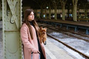 femme voyageuse touriste se promène avec ses bagages et son chien à la gare en rose photo