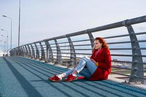 une jeune fille est assise sur le pont dans le contexte de la ville. photo