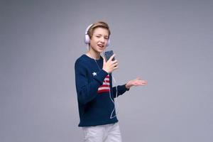 jeune homme gai portant un pull bleu avec des écouteurs de drapeau américain chantant une chanson photo