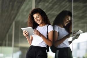 heureuse jeune femme arabe à l'aide d'une tablette numérique dans le contexte des affaires. photo