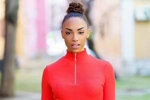 jeune femme noire en robe rouge posant dans une rue aux murs colorés photo