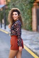 heureuse jeune femme arabe avec une coiffure frisée noire. photo