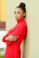 jeune femme mixte en robe rouge avec une expression sérieuse en milieu urbain. photo