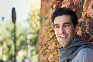 homme portant des vêtements d'hiver souriant sur fond de feuilles d'automne photo