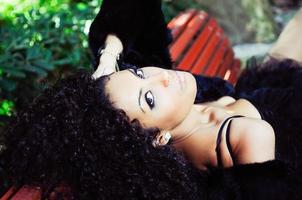 jeune femme africaine assise sur un banc dans le parc photo