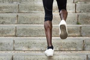 jambes athlétiques d'un homme noir qui court sur les marches de l'escalier. photo