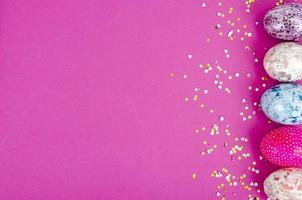 oeufs de pâques faits à la main multicolores et confettis sur fond rose. notion minimale. vue d'en-haut. espace pour le texte. photographie de studio photo
