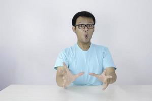 wow et visage choqué d'un jeune homme asiatique avec un geste de la main ouverte. concept de modèle publicitaire avec chemise bleue. photo