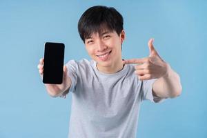 jeune homme asiatique utilisant un smartphone sur fond bleu photo