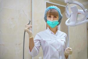 une femme dentiste tient une machine à bore dans sa main photo