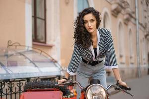 belle jeune femme assise sur une moto dans une rue de la ville photo