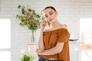 belle jeune femme se tient dans la chambre sur fond de mur de briques blanches photo