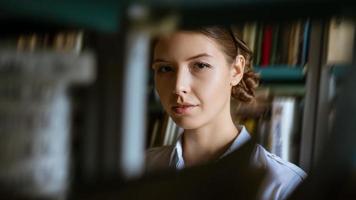 portrait d'une jeune femme sur fond de livres dans la bibliothèque photo