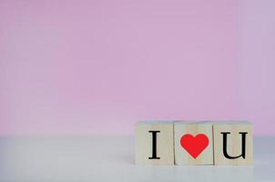 cubes en bois avec je t'aime coeur symbole sur fond rose et espace de copie. photo