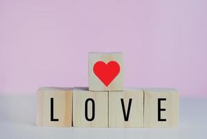 cubes en bois avec coeur de symbole d'amour sur fond rose et espace de copie. photo