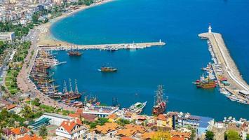 vue de dessus de la plage d'alanya sur la montagne avec le ferry de la côte sur la mer bleue et le fond de la ville portuaire - belle plage de cléopâtre alanya turquie paysage voyage point de repère photo