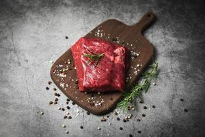 steak de boeuf cru aux herbes et épices - viande de boeuf fraîche tranchée sur fond de planche à découper en bois photo