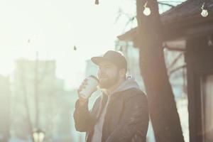 homme avec une tasse de café marchant le long de la ville photo