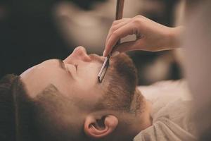 homme avec une barbe sur une chaise dans le salon de coiffure photo