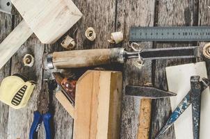 les outils de charpentier sur un banc en bois, un avion, un ciseau, un maillet, un ruban à mesurer, un marteau, des pinces, des pinces, un niveau, des clous et une scie photo