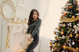 jeune fille élégante avec des cadeaux de noël et une décoration de nouvel an. tonalité de couleur douce et chaude. photo