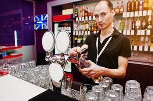 le barman verse une bière au bar du club photo