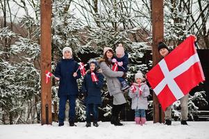 famille avec des drapeaux du danemark en plein air en hiver. voyage dans les pays scandinaves. les danois les plus heureux. photo