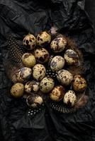 oeufs de caille et plumes sur papier d'emballage froissé noir. photo