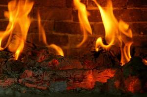 bois de chauffage et braises. les flammes flamboyantes des flammes du feu dans la cheminée. photo