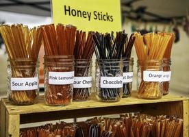 bâtons de miel d'abeille frais biologiques exposés. marché des fermiers. les bâtonnets de miel sont des pailles en plastique pratiques remplies de miel aromatisé gastronomique.