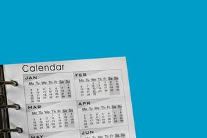 calendrier sur fond bleu pour la planification. gros plan sur un calendrier blanc avec un planning mensuel pour prendre rendez-vous ou gérer votre planning au quotidien. photo
