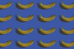 répéter la banane sur fond bleu. la lumière du soleil de la mode. modèle d'été à partir de bananes fraîches.
