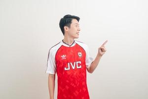 bangkok, thaïlande - 27 novembre 2021 - jeune homme asiatique portant une chemise d'arsenal avec un fond blanc. photo