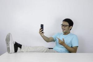 jeune homme asiatique choqué quand il regarde un smartphone avec une jambe sur la table photo