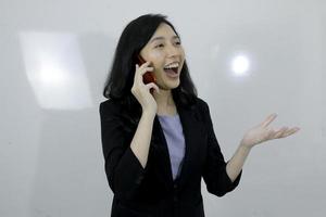 une jeune fille asiatique d'affaires est heureuse d'utiliser un ordinateur portable et de parler au téléphone photo