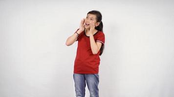 une petite fille avec les mains tenant près de sa bouche et les mains jointes à la bouche. fond blanc isolé. annonce, concept d'attention photo