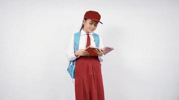 Fille de l'école primaire asiatique lisant un livre heureusement isolé sur fond blanc photo