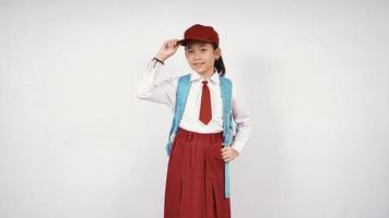 petite fille asiatique portant chapeau et sac d'école souriant joyeusement sur fond blanc isolé photo