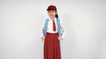 petite fille asiatique portant chapeau et sac d'école souriant joyeusement sur fond blanc isolé photo