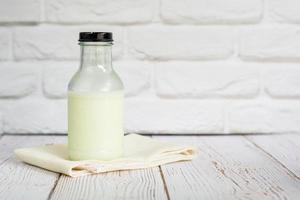 bouteille de lait frais sur une nappe blanche avec mur dans la cuisine avec espace de copie pour votre texte. riche en calcium et en vitamines. bonne boisson pour le matin. photo