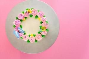 crème au beurre de roses roses décorées oo gâteau d'étang à la vanille sur fond rose avec espace de copie servi dans la fête d'anniversaire et le mariage. délicieuse boulangerie sucrée pour quelqu'un que vous aimez. photo