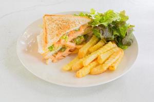 sandwich avec saucisse, mayonnaise et ketchup sur plaque blanche avec frites et laitue fraîche. notion de restauration rapide. photo