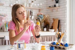 jeune jolie femme colorant des oeufs de pâques dans la cuisine photo